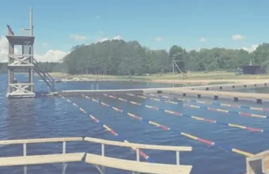 Väinjärve välibassein, millel on Top Marine toodetud ujuvkaidega ujumisrajad ja kõrge hüppetorn, ümbritsetud loodusest ja sinisest taevast.